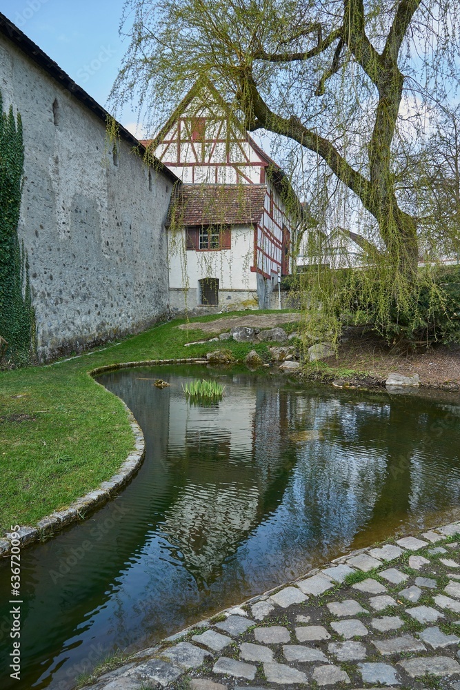 section of the medieval outer wall of the town of Wangen i.A. (Germany) with a water course in which a house is reflected section of the medieval outer wall of the town of Wangen i.A. (Germany) with a water course in which a house is reflected