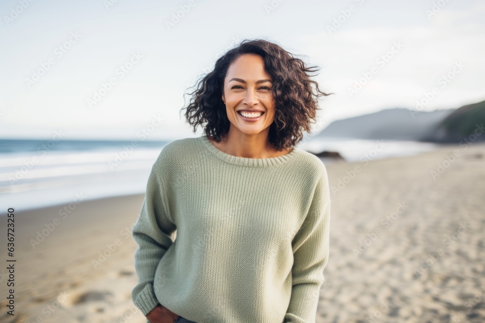 Lifestyle portrait of a Indonesian woman in her 40s in a beach background wearing a cozy sweater