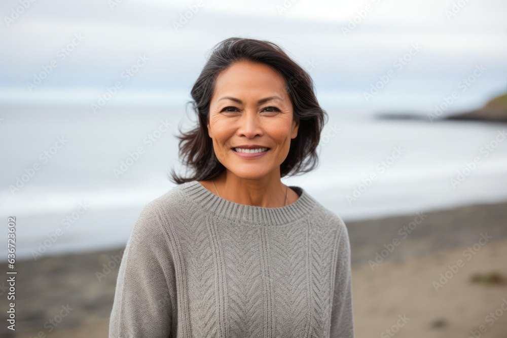 Lifestyle portrait of a Indonesian woman in her 50s in a beach background wearing a cozy sweater Lifestyle portrait of a Indonesian woman in her 50s in a beach background wearing a cozy sweater