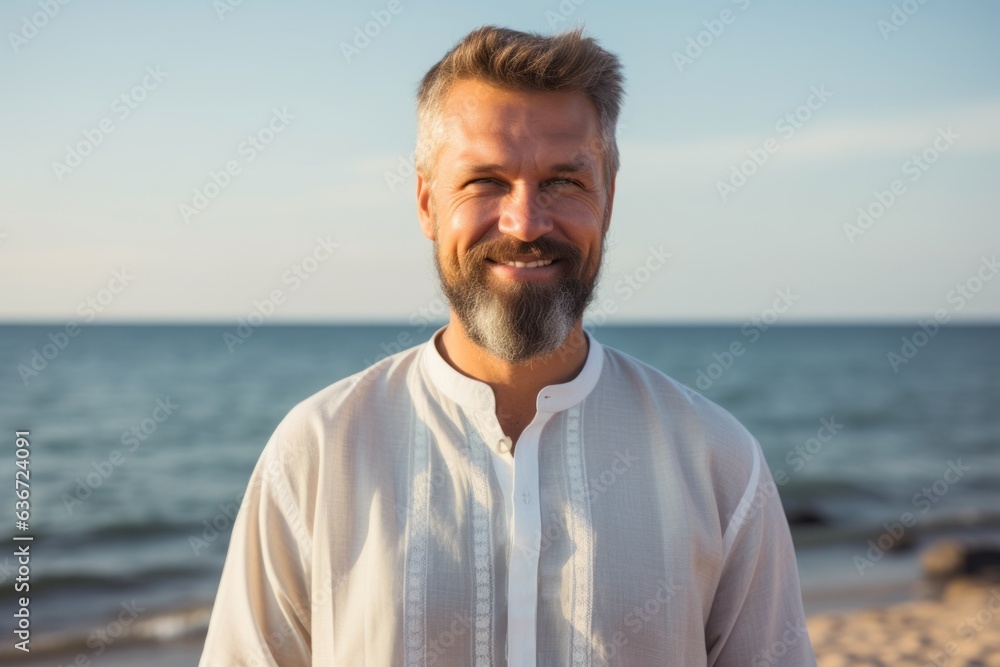 Medium shot portrait of a Russian man in his 40s in a beach background wearing a simple tunic