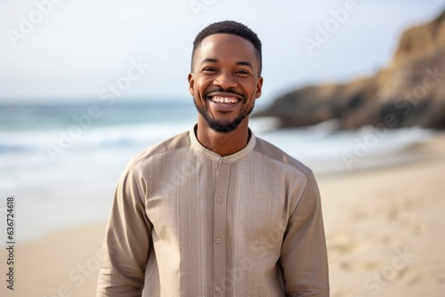 Lifestyle portrait of a Nigerian man in his 30s in a beach background wearing a chic cardigan