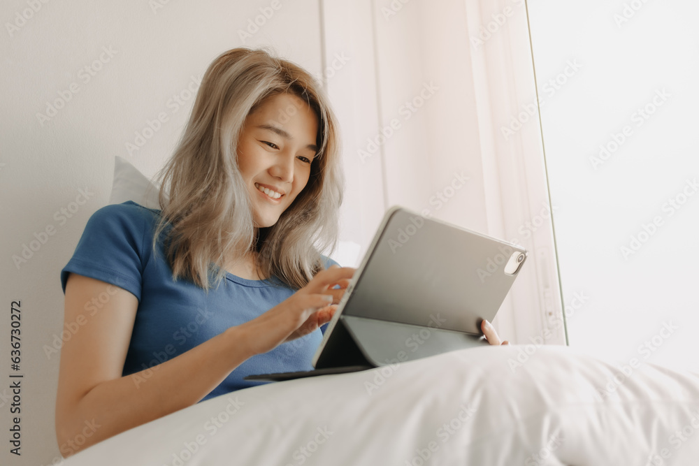Happy freelance asian woman work on tablet on the hotel bed on travel trip. Happy freelance asian woman work on tablet on the hotel bed on travel trip.
