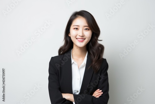 Portrait of a Chinese woman in her 20s in a white background wearing a classic blazer
