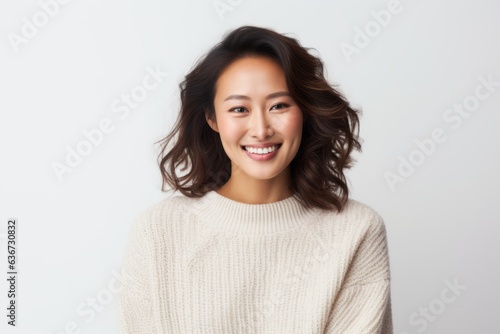 Portrait of a Chinese woman in her 30s in a white background wearing a cozy sweater © Eber Braun