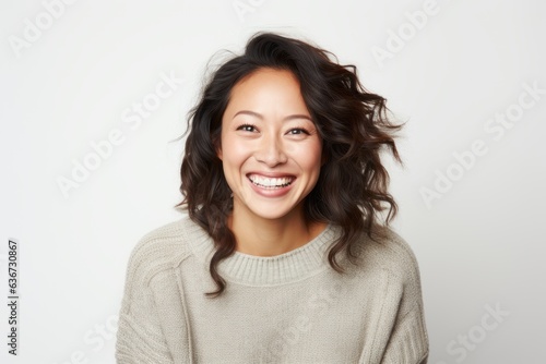 Portrait of a Chinese woman in her 30s in a white background wearing a cozy sweater