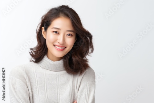 Portrait of a Chinese woman in her 30s in a white background wearing a cozy sweater