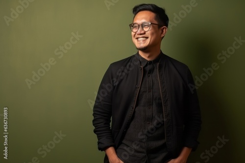 Portrait of a young Asian man wearing eyeglasses against green background