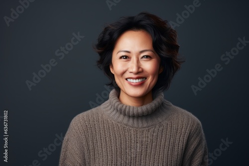 Portrait of a Chinese woman in her 40s in a black background wearing a cozy sweater © Eber Braun