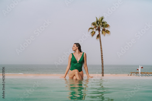 Chica joven delgada posando y descansando en piscina de hotel de lujo en andalucia