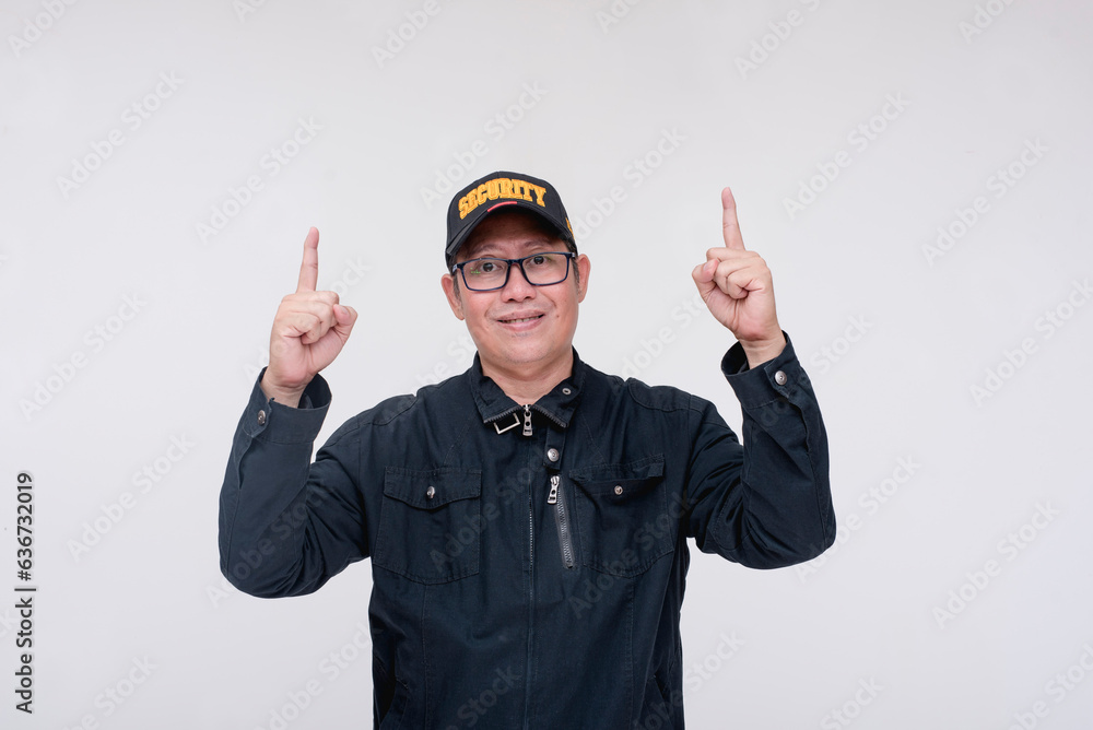 A friendly and helpful asian male security guard points up with his finger. Directing or advising someone. Isolated on a white background. A friendly and helpful asian male security guard points up with his finger. Directing or advising someone. Isolated on a white background.