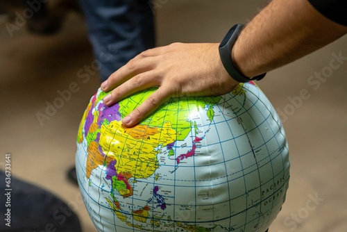 Closeup of a person's hand on a globe with a blurry background