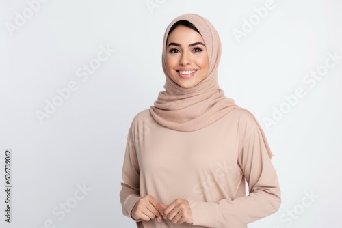 Medium shot portrait of a Saudi Arabian woman in her 30s in a white background wearing a cozy sweater
