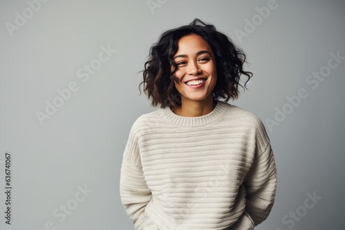 Portrait of a smiling young woman standing isolated on a gray background