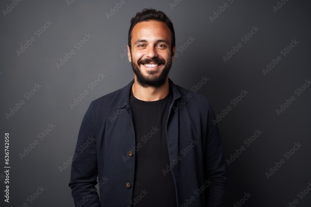 Portrait of a handsome Indian man smiling at the camera while standing against grey background