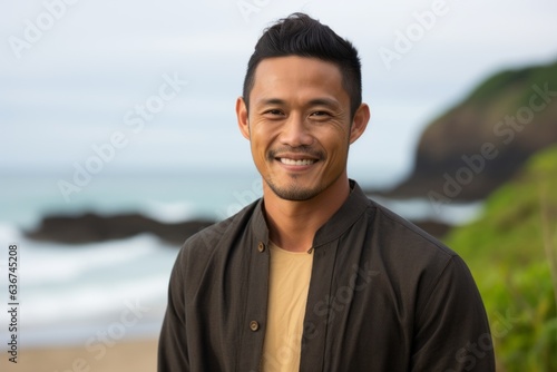 Portrait of young handsome Asian man smiling at camera on the beach
