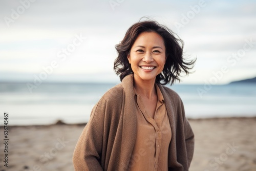 Portrait of happy mature woman smiling at camera on beach during autumn day