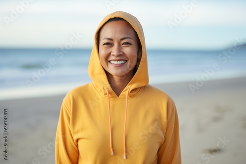 portrait of smiling young asian woman in hoodie at beach