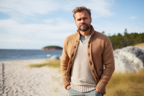 Portrait of a handsome man standing on the beach at autumn day