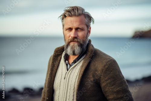 Portrait of a handsome mature man on the beach, wearing a warm coat.