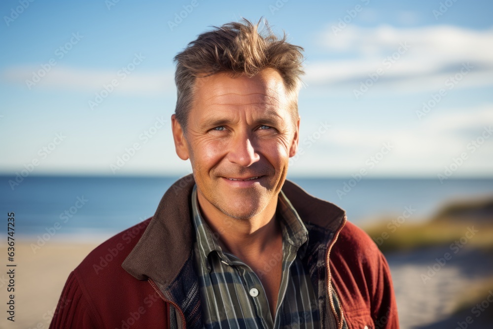 Portrait of a smiling man standing on the beach looking at camera