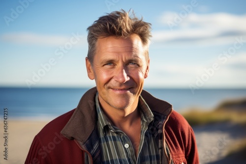 Portrait of a smiling man standing on the beach looking at camera