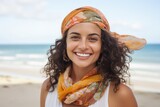 Portrait of a smiling young woman with headscarf on the beach