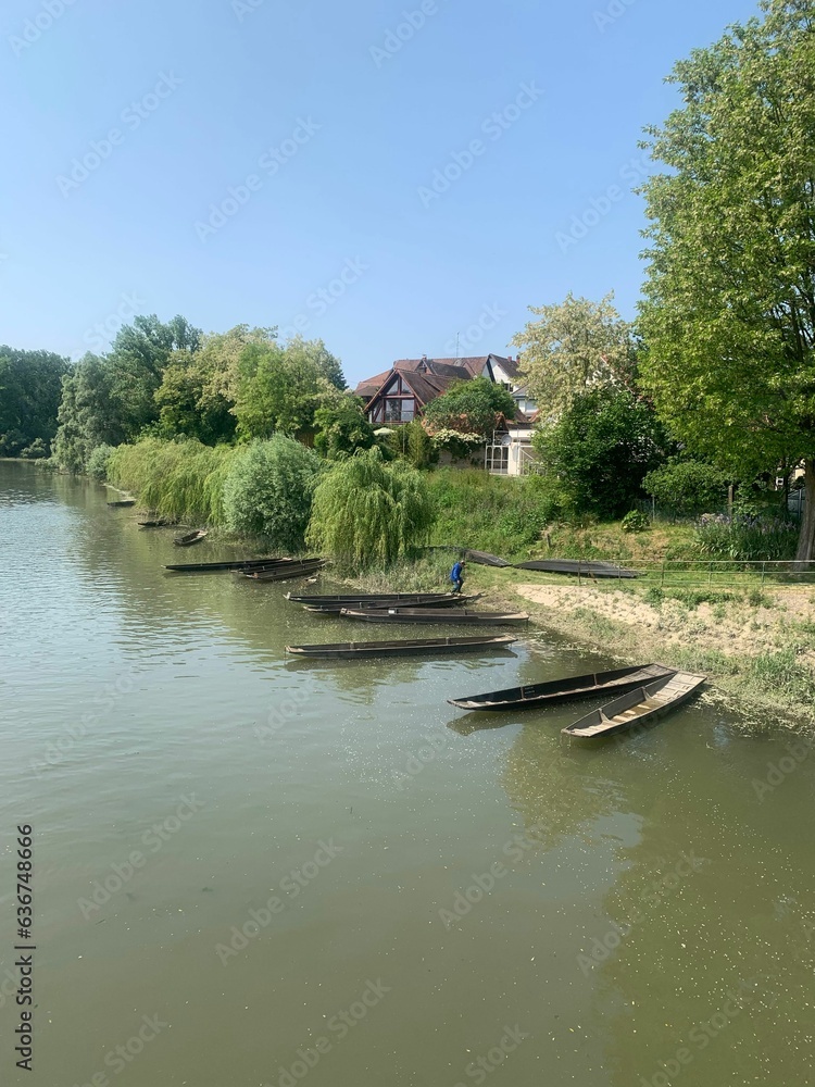 Obraz premium a river with boats on the bank of it, and trees around