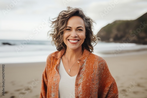 Portrait of smiling mature woman with curly hair standing on sandy beach