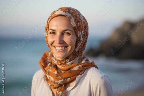 Portrait of happy young muslim woman wearing headscarf at the beach