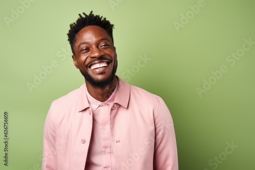 Portrait of a Nigerian man in his 20s in a pastel or soft colors background wearing a chic cardigan