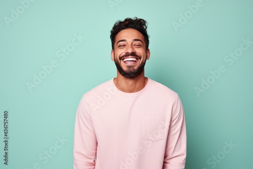 Portrait of a Saudi Arabian man in his 20s in a pastel or soft colors background wearing a chic cardigan