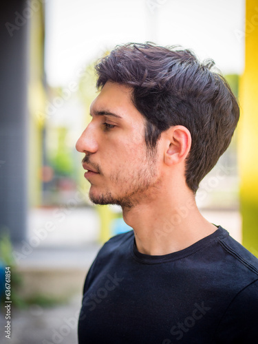 Head and shoulder sideview shot of one handsome young man in urban setting
