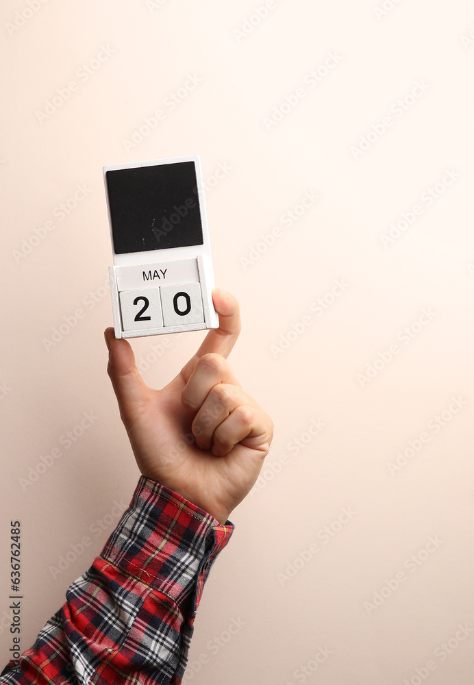 Date May 20, block calendar in male hand on beige background Date May 20, block calendar in male hand on beige background