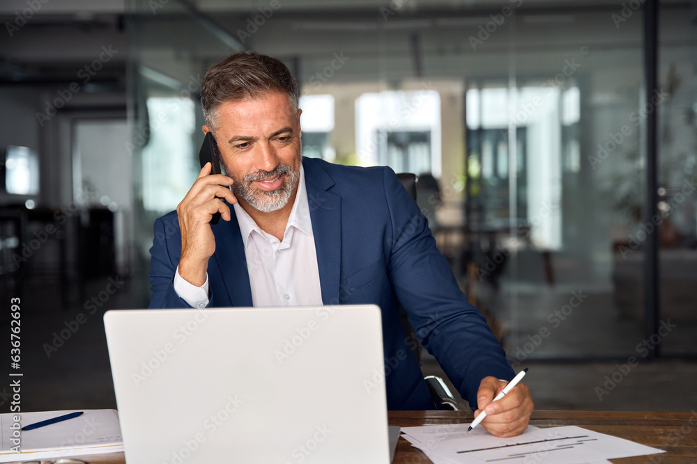 © Stock 4 You - Middle aged Latin or Indian businessman having call on smartphone with business partners or clients. Smiling mature Hispanic man sitting at table talking by mobile cellphone and make notes in office. © Stock 4 You - Middle aged Latin or Indian businessman having call on smartphone with business partners or clients. Smiling mature Hispanic man sitting at table talking by mobile cellphone and make notes in office.