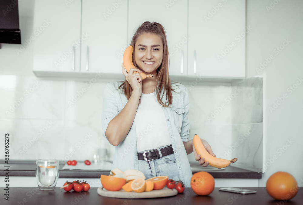 Cheerful young woman talking over banana in modern kitchen Cheerful young woman talking over banana in modern kitchen