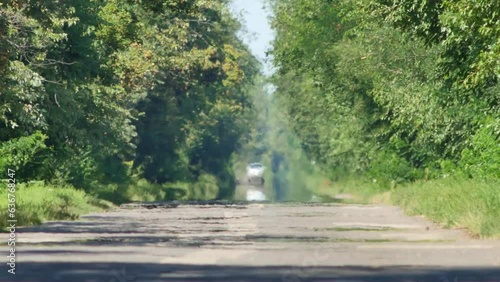 Heat waves with mirage over road on hot summer day. Car drives along road surrounded by green trees. Period of abnormally hot weather and extreme heat. Global warming and climate change concept video photo
