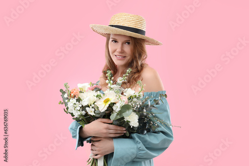 Beautiful woman in straw hat with bouquet of flowers on pink background