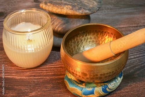 a wooden stick and a singing bowl on a table near candles
