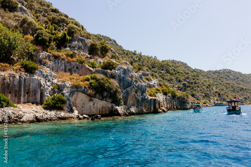 Fototapeta Naklejka Na Ścianę i Meble -  Beautiful view of the Mediterranean Sea with yachts. Picturesque landscape of blue ocean and green mountains on a sunny summer day. The sunken city of Kekova, Türkiye - 28 July 2023