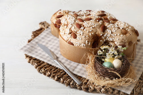 Delicious Italian Easter dove cake (Colomba di Pasqua) and decorative eggs on white wooden table