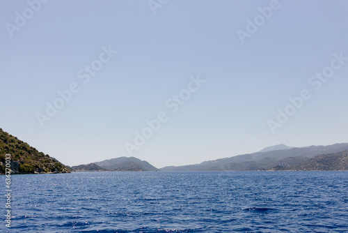 Beautiful view of the Mediterranean Sea with yachts. Picturesque landscape of blue ocean and green mountains on a sunny summer day. The sunken city of Kekova, Türkiye - 28 July 2023 © Liudmila