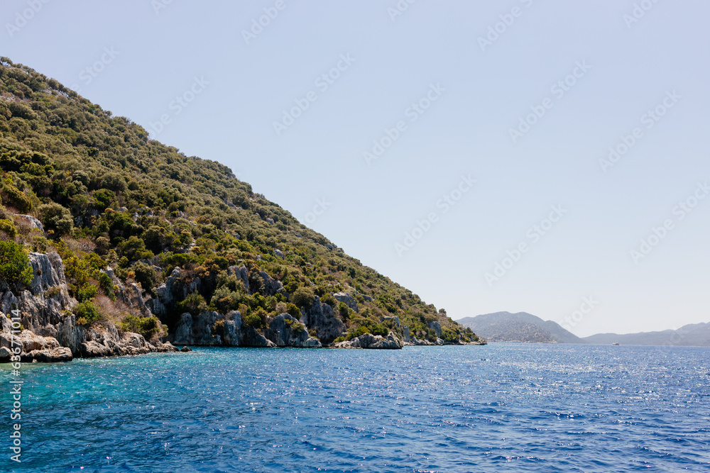 Beautiful view of the Mediterranean Sea with yachts. Picturesque landscape of blue ocean and green mountains on a sunny summer day. The sunken city of Kekova, Türkiye - 28 July 2023