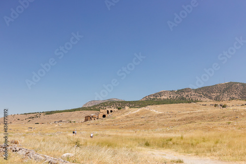Half-ruined buildings of the ancient city, Journey to the old city. Preserved old columns against the backdrop of a mountain landscape. Hierapolis Ancient City, Pamukkale, Türkiye - July 29, 2023