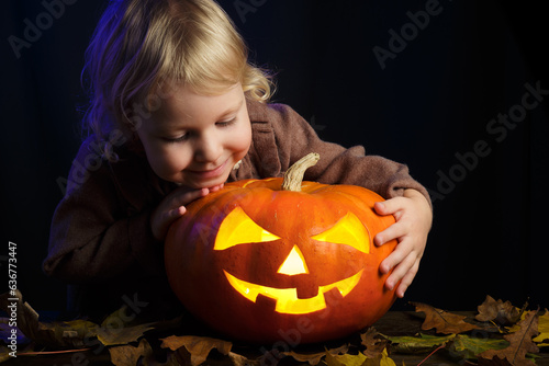 Little fun girl holding Halloween pumpkin. The child are shocked by the glowing orange pumpkin. Halloween concept