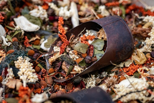 Metal container filled with a pile of autumn leaves, twigs, and flowers