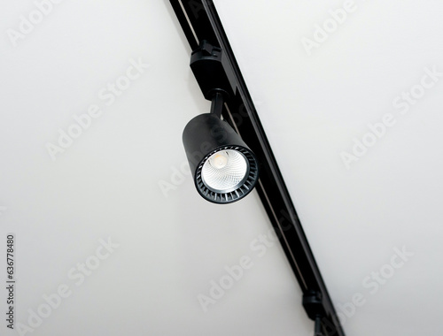 Background Led track lamp on the ceiling in the interior. Interior spotlight in black color. Modern track lamp with a lot of swivel lamps. The concept of lighting in the house.