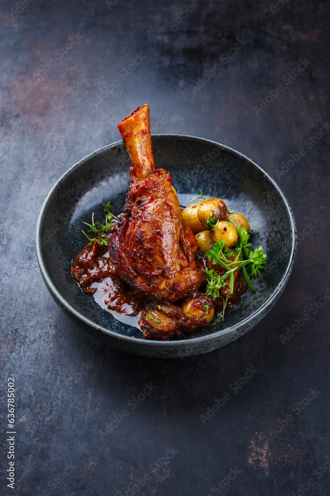 Traditional braised slow cooked lamb knuckle in red wine sauce with mini roast potatoes and