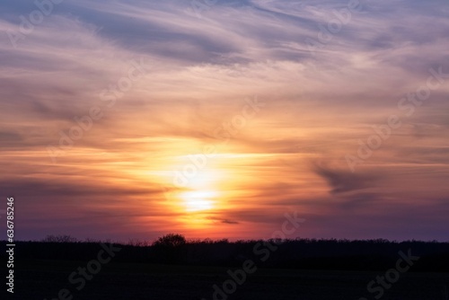 Beautiful sunrise over the silhouette of a field. © Brobert/Wirestock Creators