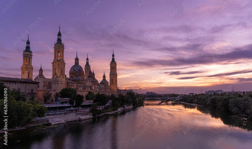 Basilica of Nuestra Senora del Pilar of Zaragoza at sunset with river reflecting purple cloudy sky