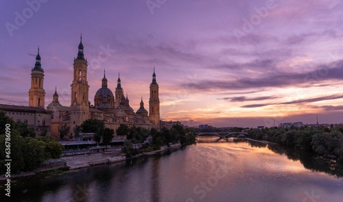 Basilica of Nuestra Senora del Pilar of Zaragoza at sunset with river reflecting purple cloudy sky